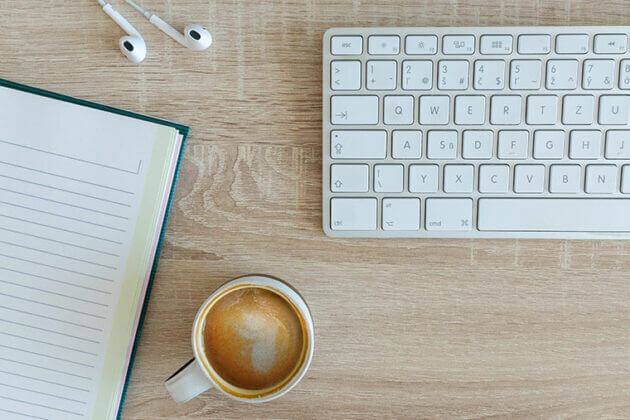 Notebook, ear phones and keyboard on a desk