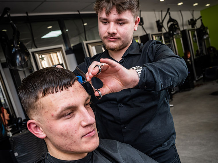 A hairdressing student cutting a client's hair