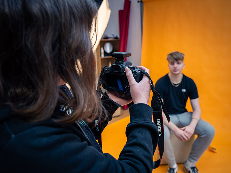 A photography student taking a photo of another student