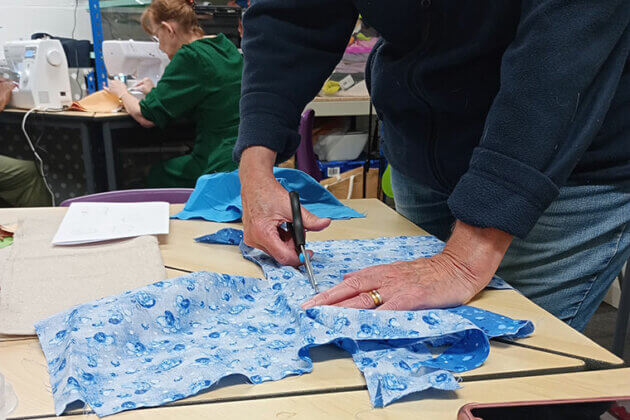 Someone cutting a piece of material ready to sew