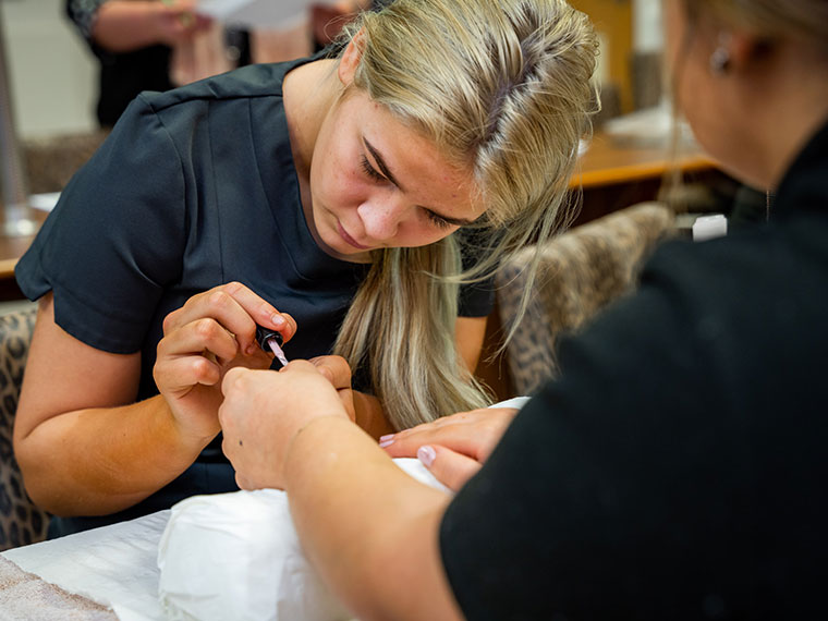 A student working on a client's nails in the NNC salon