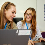 Two business students sat at laptops