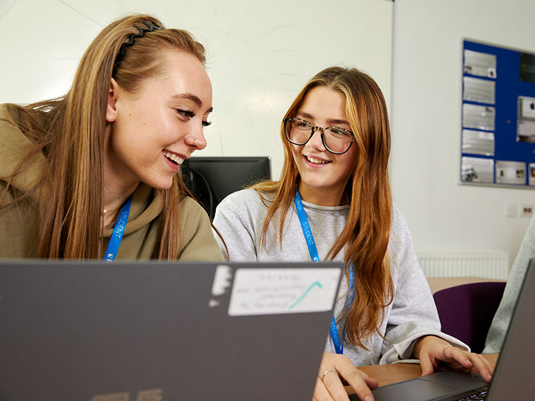 Two business students sat at laptops