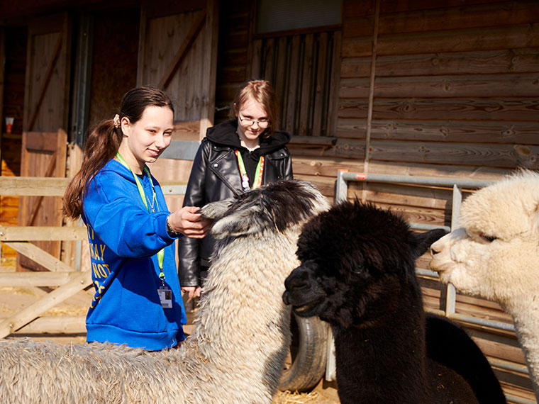 Two animal care students outside stroking animals