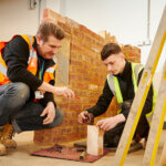 A tutor supporting a bricklaying student with their work