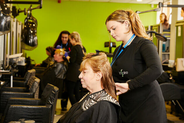 A student working on a client's hair in the salon