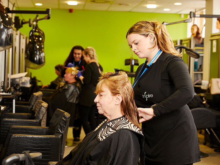A student working on a client's hair in the salon