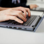 A close up of hands typing using a laptop