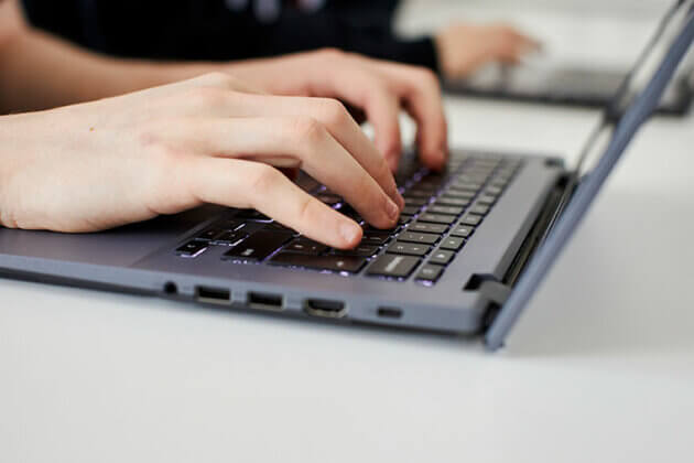 A close up of hands typing using a laptop