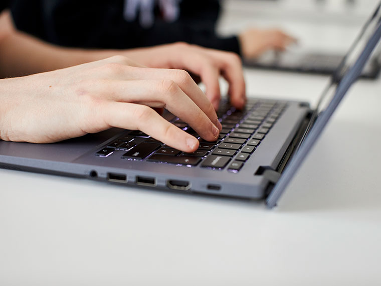 A close up of hands typing using a laptop