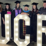 Students at their graduation stood at large UCR lit up letters