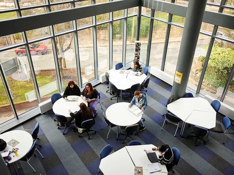 Looking down at students sat at tables in the UCR library from above