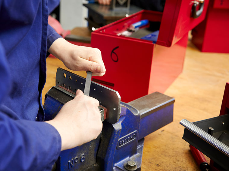 A close up of an engineering student using a vice