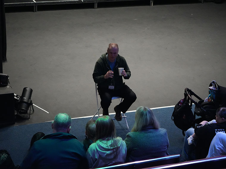 People sat in the studio theatre listening to a performing arts tutor speak during a Rotherham College open event