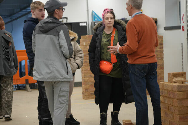 People stood in the bricklaying workshop speaking to a tutor