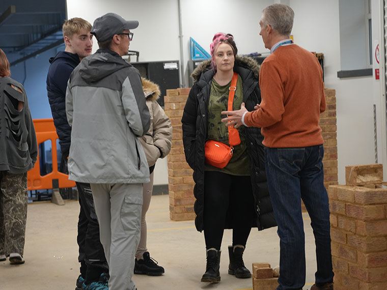 People stood in the bricklaying workshop speaking to a tutor