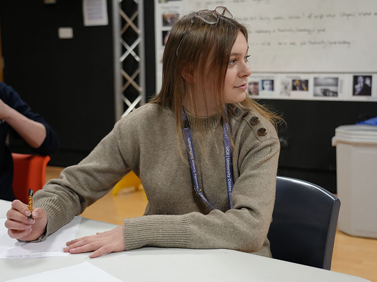 Performing Arts student Alea sat at a desk holding a pen ready to write