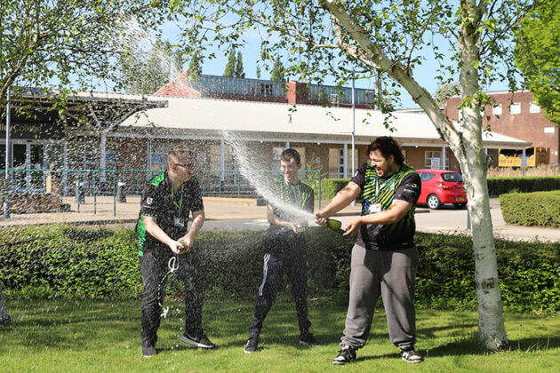 Three esports students celebrating winning a competition