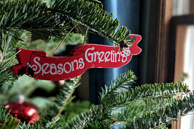 Seasons Greetings written on a decoration on a Christmas tree