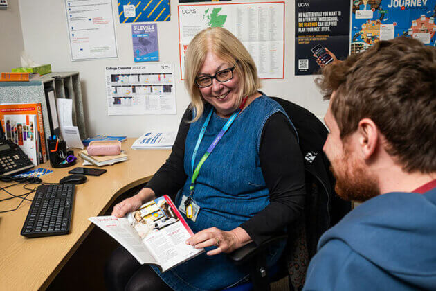 A member of staff sat at a desk speaking to someone