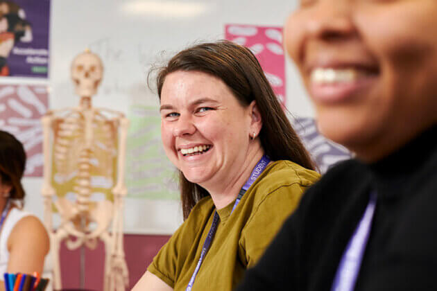 Two smiling health students with a skeleton in the background