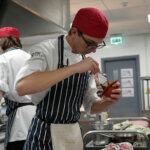 A catering student making food in the kitchen