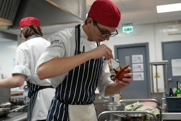 A catering student making food in the kitchen