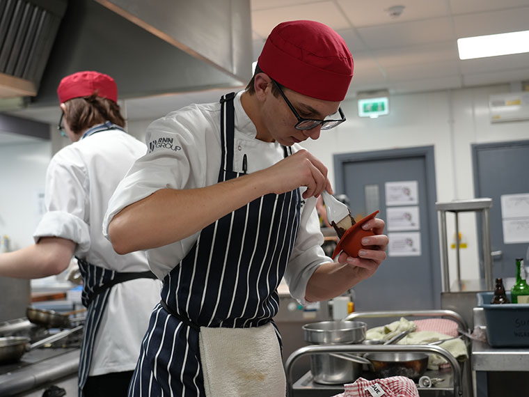 A catering student making food in the kitchen