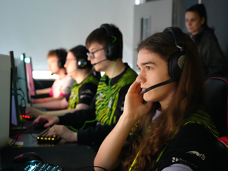 A line of Esports students with headphones on sat in front of computers
