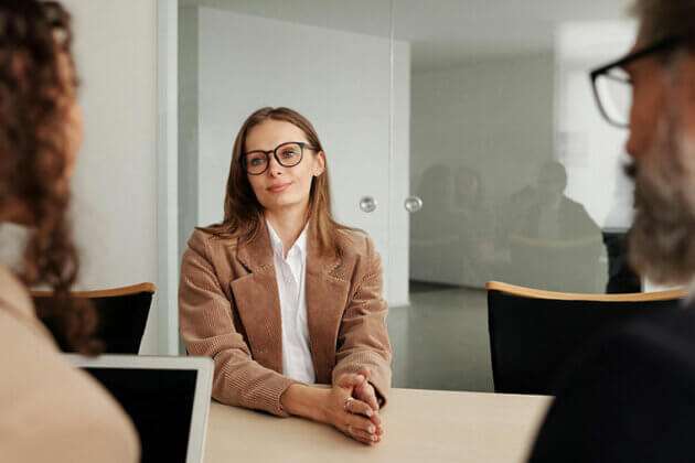 Someone sat at a desk being interviewed by two people