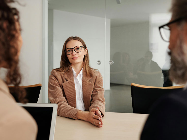 Someone sat at a desk being interviewed by two people