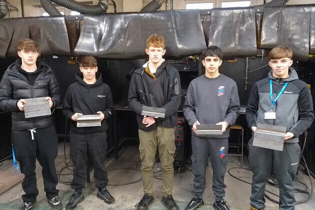 Five learners holding their welding work