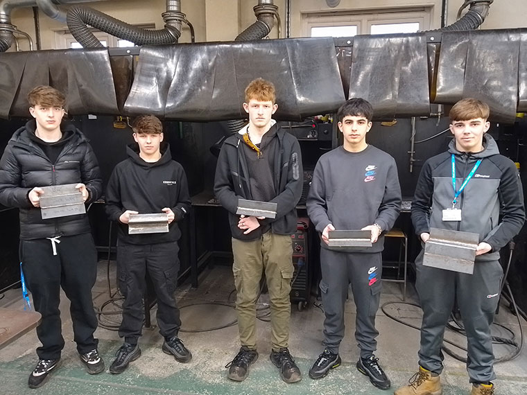 Five learners holding their welding work