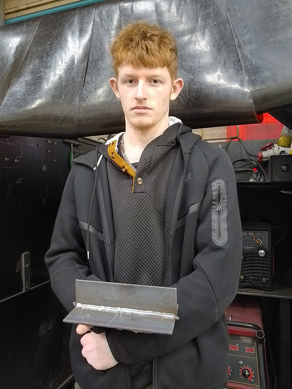 A Level 2 Welding learner holding his welding work