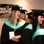 Graduands lining up ready to enter the ceremony room, one person with a big smile
