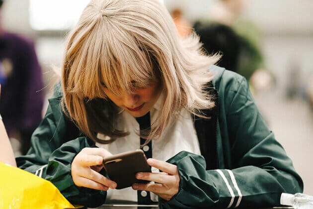 A person sat at a desk looking down at their mobile phone