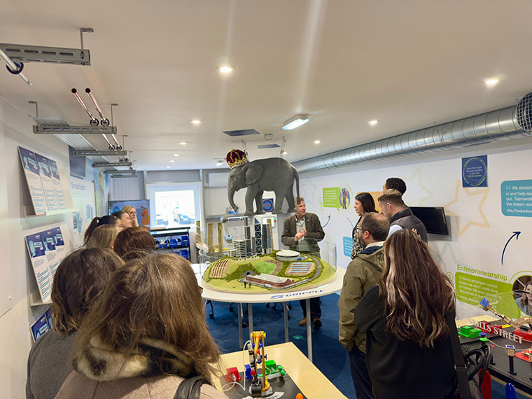 A group of people stood in a room looking at different things around the room