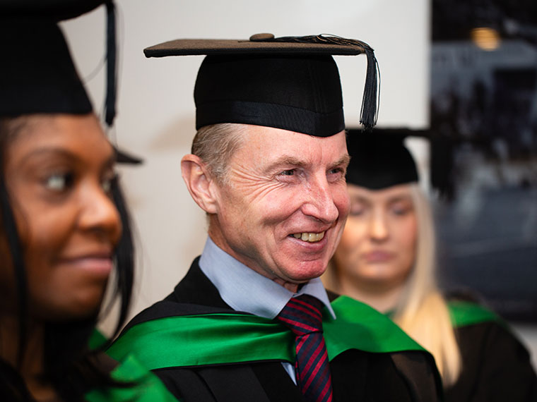 A head shot of a smiling graduation in cap and gown