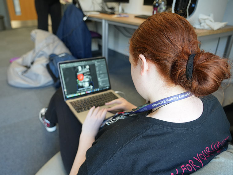 Head shot of Chelsie Ellis, sat on a bean bag looking at a laptop