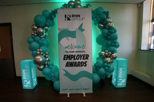A circle of balloons and a pull up banner at the RNN Group's Employer Awards