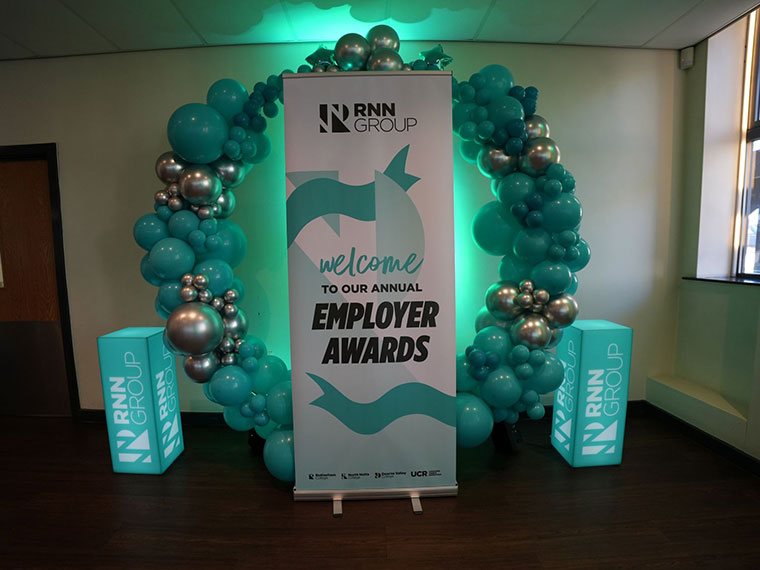 A circle of balloons and a pull up banner at the RNN Group's Employer Awards