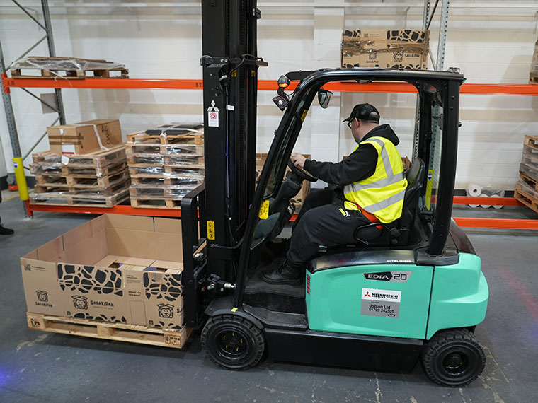 Someone driving a forklift truck lifting boxes