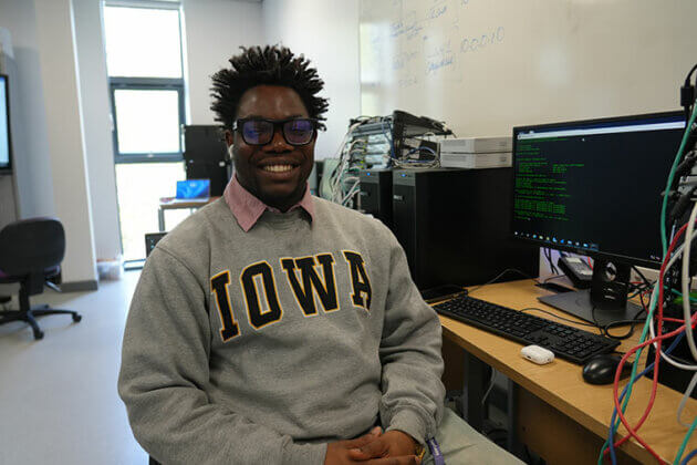 A student sat in a classroom smiling at the camera