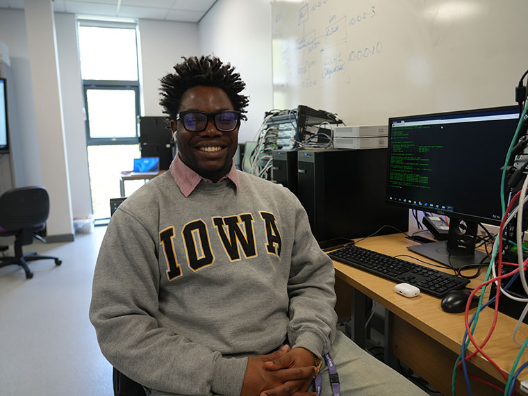 A student sat in a classroom smiling at the camera