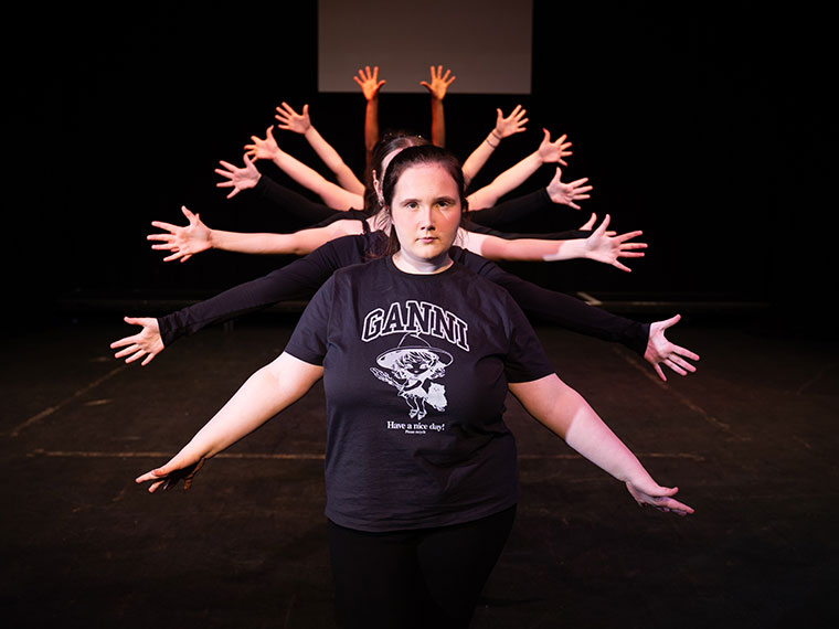 A group of performance students stood in a line behind each other with their hands up in the air