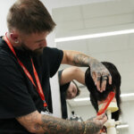 An adult learner cutting hair in the College's training salon