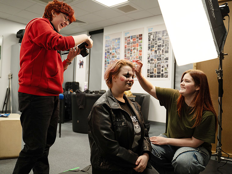 Three students preparing for a photoshoot in the photography studio