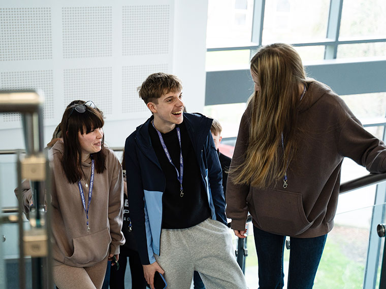 Three students talking whilst walking up the stairs