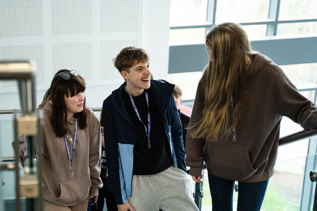 Three students talking whilst walking up the stairs