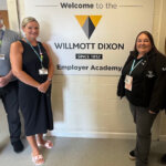 A sign that reads 'Welcome to Willmott Dixon Since 1852 Employer Academy' two people stood at each side of the sign